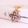 Exquisite gold-tone clover keychain with black and white rhinestones and a floral pendant - Black