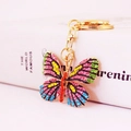 Golden butterfly keychain with colorful sparkling rhinestones on white background - Green and Dark Pink