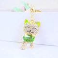 Golden cat keychain with white rhinestones holding a large green crystal gemstone - Green