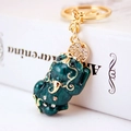 Green enamel Pi Xiu keychain with gold metal frame and white rhinestones on white book - Individual Packaging / Dark Green