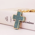 Portachiavi a croce dorata con strass azzurro cielo su un elegante sfondo di un libro - Blu