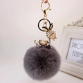 Detailed close-up of dark grey faux fur keychain with a gold donkey rhinestone pendant - Black Ears + Gray