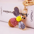 Pink and orange crystal bee keychain with gold hardware on Anna Karenina book - Gray