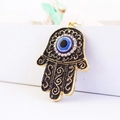 Gouden Hamsa Hand sleutelhanger met blauw boze oog en kristallen op witte achtergrond - Zwart