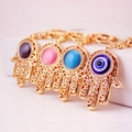 Hamsa Hand Schlüsselanhänger mit Evil Eye Kristallen und Strasssteinen in bunten Farben - Einzelpackung / Zufällige Farbe