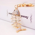 Creative golden fishbone keychain with colorful crystals and lobster clasp on book - Colorful