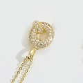 Pendentif noeud doré élégant serti de micro-zircons sur une fine chaîne dorée brillante - Lettre Q