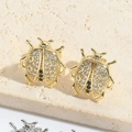 Golden ladybug stud earrings with zircon inlay shown on natural stone background - Beetle (Gold)
