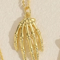 Polished golden skeleton hand pendant necklace with a delicate link chain for daily wear - Skeleton Hand