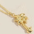 Chic gold palm tree pendant necklace with delicate link chain on a neutral fabric background - Coconut Tree / Gold