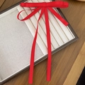 Primo piano di un grande fiocco in raso rosso con lunghi nastri su un vassoio beige - Rosso