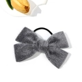 Detail view of a soft grey plush bow hair scrunchie with elastic band and decorative flower - Gray