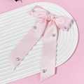 Dettaglio del fiocco in raso rosa con fibbie a cuore d'argento e lunghi nastri su vassoio - Rosa