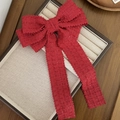Detalle del lazo de pelo en tweed rojo con hilos brillantes y cintas largas en una bandeja - Rojo