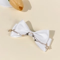 Close-up of white satin bow hair clip with gold star chain charms on a soft beige background - White - Chain Star Charms