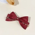 Detailed shot of burgundy satin bow hair clip with gold star chain and silk texture finish - Wine Red - Chain Star Charms