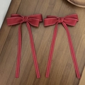 Detail of red bow hair clips with white stitching and long ribbons on wooden surface - Bow Ribbon Style / Red