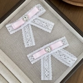 Detailed macro of white lace hair clips with pink ribbons and heart-shaped rhinestones - Pink (1 Pair)