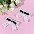 Close-up of lace bow hair clips with black heart rhinestone and satin ribbon details - Black (1 Pair)