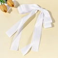 Detalle de un elegante lazo de raso blanco con cintas largas sobre un fondo minimalista - Blanco