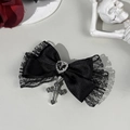 Close-up of black lace bow hair clip featuring a heart gem and vintage silver cross pendant - Black