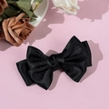 Detail of multi-layered black satin bow hair clip with elegant silk gloss on pink background - Black
