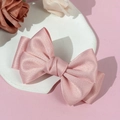 Gros plan détaillé d'une pince à cheveux nœud en satin rose avec texture de ruban - Rose