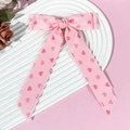Detail van roze haarclip met lange linten en schattige donkerroze hartpatronen - Roze