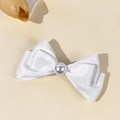 Detailed view of the white satin bow hair clip with a large pearl center ornament - White
