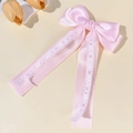 Detailed view of pink satin bow hair clip with elegant white lace ribbons and smooth texture - Pink