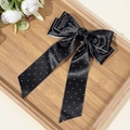Detailansicht der gepunkteten Haarklammer aus Satin mit langen Bändern auf einem Tablett - Schwarz