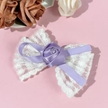 Détail d'une barrette nœud en dentelle blanche avec rose en satin violet sur fond rose - Violet