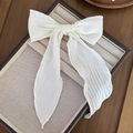 Detail of white pleated bow hair clip with long flowing ribbons on a jewelry display tray - Edge-locked Style / White