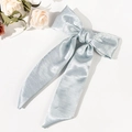 Detail of light blue satin bow hair clip with elegant long ribbons on a white background - Blue