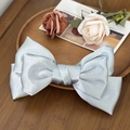 Elegant light blue satin bow hair clip placed on a wooden tray with flowers - Blue