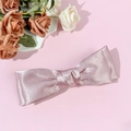 Detalle de elegante horquilla con lazo de satén rosa pálido y textura de seda suave y fina - Rosa