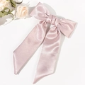 Detail einer eleganten hellrosa Satin-Haarschleife mit langen Bändern für Damen - Rosa