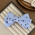 Blue and white striped bow hair clip with black heart patterns on a display tray - Blue
