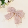 Close-up of soft pink bow hair clip with fuzzy fringe textures and elegant fabric knot - Pink