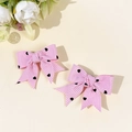 Dettaglio di fermagli per capelli a fiocco rosa a righe con motivi a cuore nero e taglio a coda - Fiocco a Coda di Rondine / Rosa