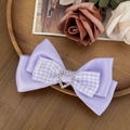 Detailed shot of a purple ribbon bow hair clip with a sparkling rhinestone heart center - Purple
