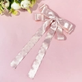 Gros plan d'une pince à cheveux à nœud rose à pois avec de longs rubans élégants - Rose