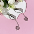 Détail de pinces à cheveux coeur argenté avec chaînes et croix sur un fond rose doux - 5#