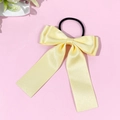 Détail d'un chouchou à nœud en satin jaune clair avec rubans sur fond rose - Jaune