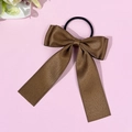 Détail du chouchou en satin marron café avec un nœud papillon et de longs rubans élégants - Marron