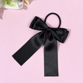 Nahaufnahme eines schwarzen Satin-Haargummis mit langen Bändern auf rosa Hintergrund - Schwarz