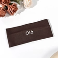 Detail of dark brown elastic yoga headband featuring white Olá lettering on white surface - Brown