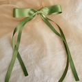 Detailed close-up of grass green satin ribbon bow hair clip with elegant long streamers - Green
