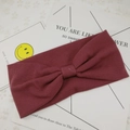 Detail of burgundy ribbed knit headband featuring a stylish central knotted bow design - Burgundy