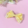 Détail d'une pince à cheveux nœud en satin jaune avec fleurs de marguerite sur fond rose - Jaune (Style Court)